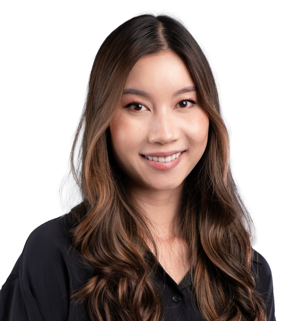 Smiling woman with long wavy brown hair wearing a black blouse, neutral gray studio background